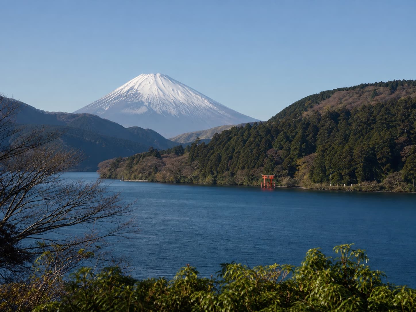 Mount Fuji beyond a calm lake and wooded hills